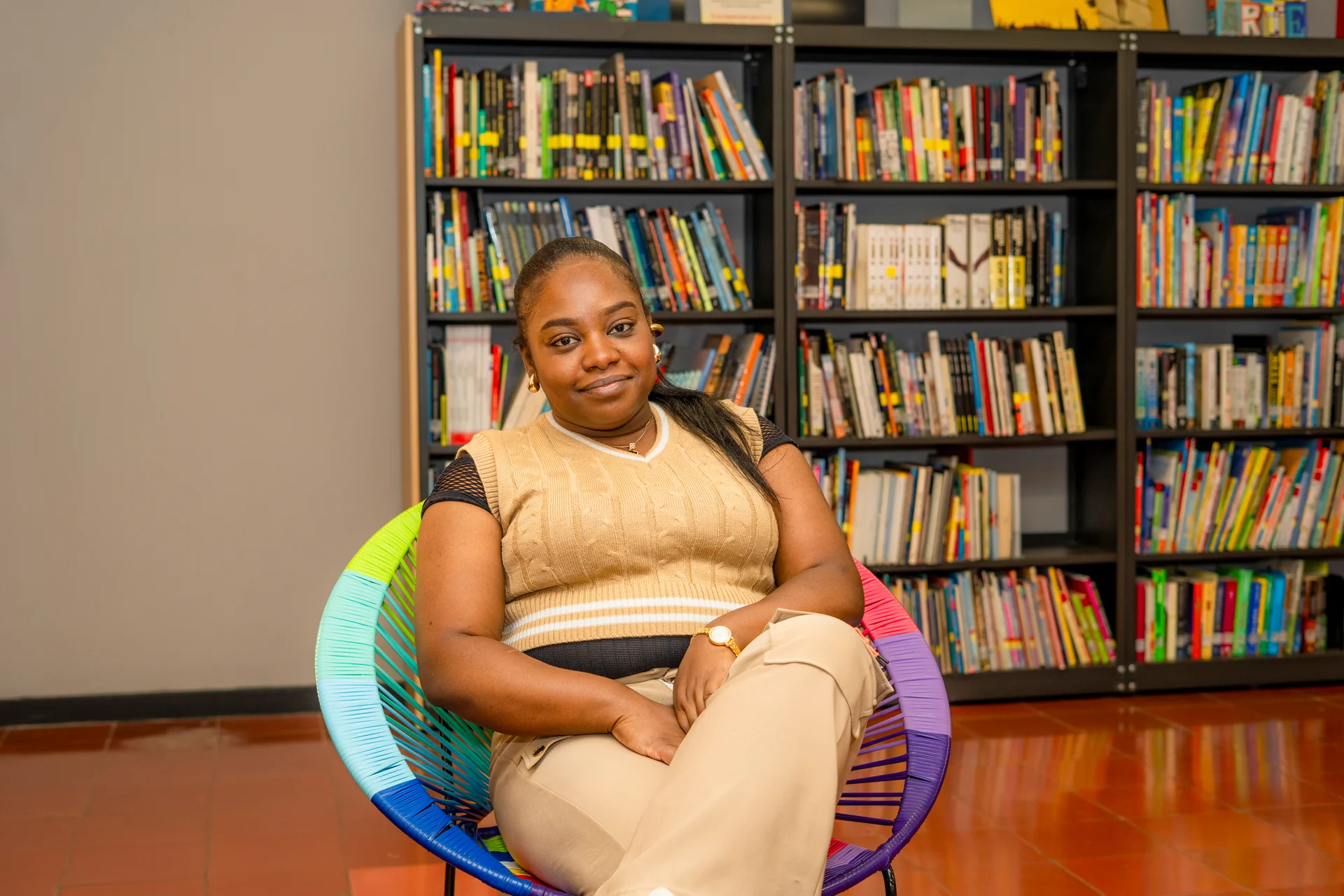 mujer sentada en una silla de colores y de fondo un ambiente de lectura