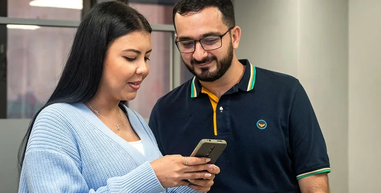 Hombre y mujer buscando en su celular opciones de empleo