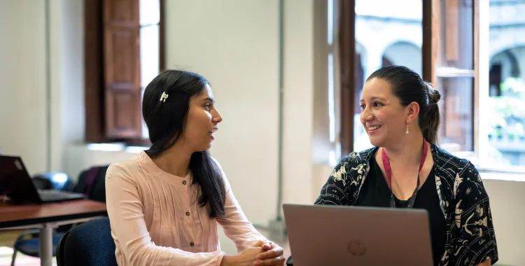 Dos mujeres conversando en entorno laboral